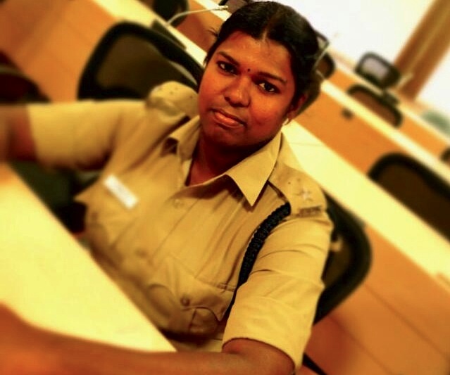 A woman police officer sits at a desk.
