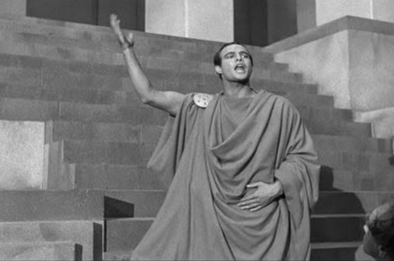 Man dressed in toga giving a speech.